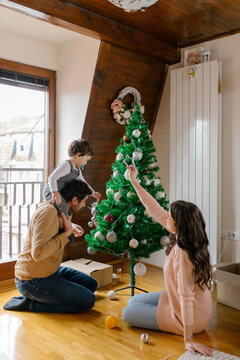 Family decorating a Christmas tree together 