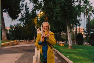 senior woman smiling using her phone at park