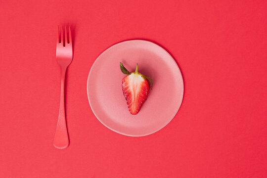 Little pink plate with half a strawberry
