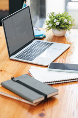 Mockup laptop computer and supplies on wooden table in vertical view.