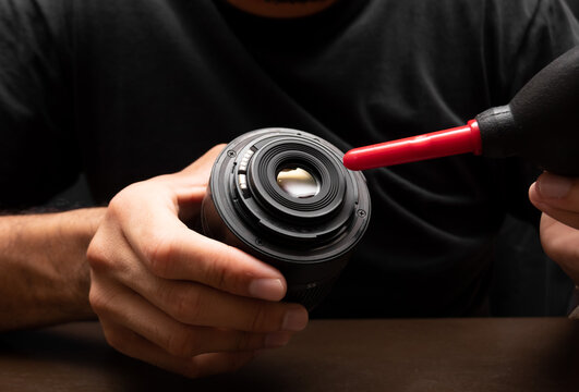 man cleaning his camera lens using a blower, camera dslr cleaning concept