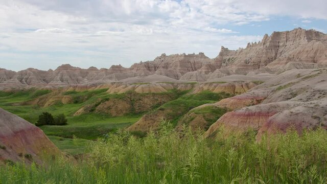 Panning view of the Badlands in South Dakota as the grass blows in slow motion on cloudy day.