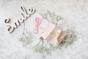 Composition with beautiful gypsophila flowers and present boxes on light background