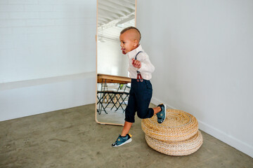Young bi-racial boy jumps from jute cushion onto floor