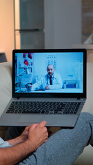 Sick man having online telemedicine consultation during covid-19. Caucasian male sitting in front of laptop disscusing with medical physician about illness symptoms working on healthcare treatment