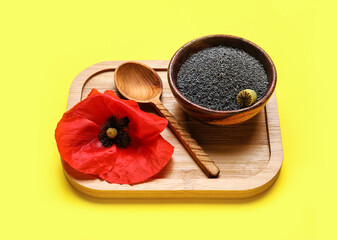 Bowl with poppy seeds and flower on color background