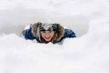 young girl digging a tunnel in the snow