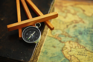 Travel and adventure search concept. Vintage aged map with a shabby book and compass. Shabby book and compass on the table.