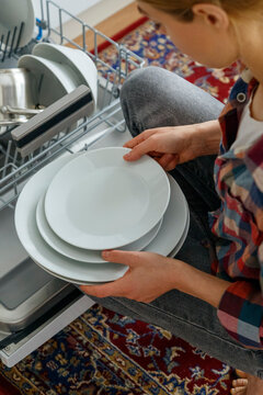 Crop female using dishwasher in kitchen