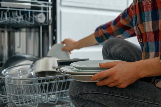 Crop housewife putting plates into dishwasher