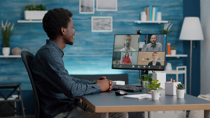 Obraz na płótnie Canvas African american man on online internet conference chat with his coworkers, remote working from home, using teleconference web communication with webcam. Black guy distance technology talking