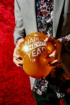 man smashing a balloon that reads happy new year