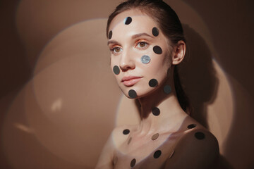 Female model with silver circles on face
