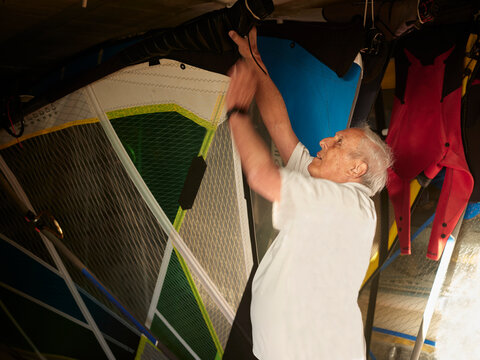 Aged man preparing sail for windsurf
