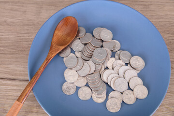Coins and wooden spoon on the plate