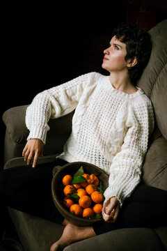Cute, curly-haired girl sitting in armchair and dreaming about better future. 