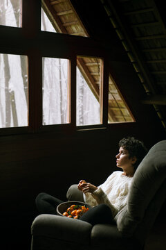 Cute, curly-haired girl sitting in armchair and dreaming about better future. 