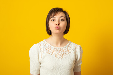 Photo of affectionate adorable woman keeps lips rounded wants to kiss someone with love flirts with...