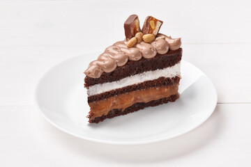 Slice of chocolate sponge cake with nougat, caramel and nuts
