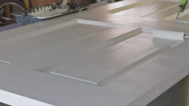 Handyman home renovation painter of painting doors trim using hand roller painting with gloves