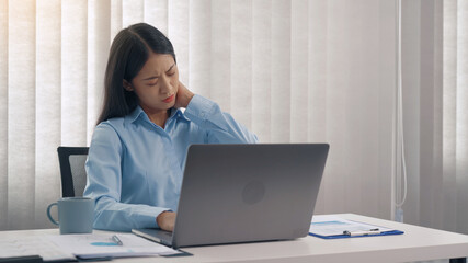 Young asian woman is sitting in a corporate office and has pain in her neck.