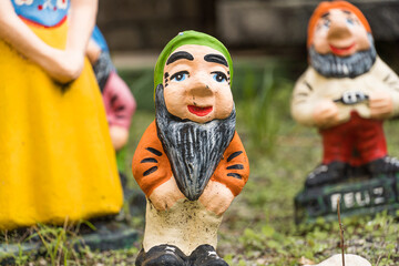 Garden with sculpture of Snow White and the seven dwarfs. Colorful pottery dolls. Selective focus.