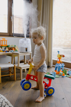 baby boy playing with a plastic bike indoors
