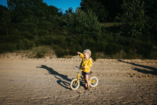 Boy with yellow raincoat and bike on the beach