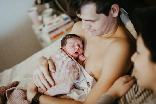 Newborn baby resting skin to skin with dad