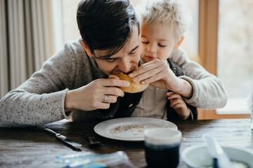 father and son sitting on the kitchen table eating pistolets