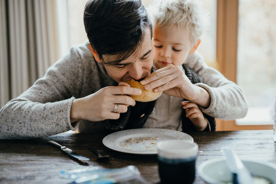 father and son sitting on the kitchen table eating pistolets