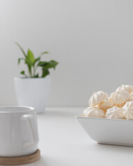 cream meringues in a bowl with cup on a white background 