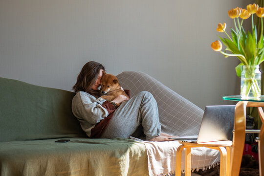 Woman on sofa cuddling with dog