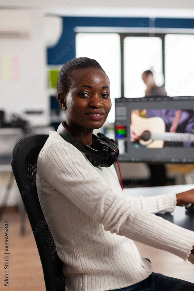Aufkleber african video editor looking at camera smiling editing video project in post production software wor