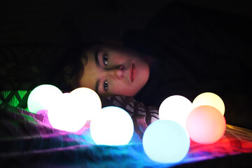 Teenager lays in the dark with light orbs around him