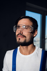 Builder in blue overalls, white shirt and goggles