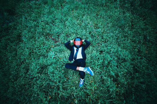 Young Black Man in Suit and Helmet Laying On Green Grass