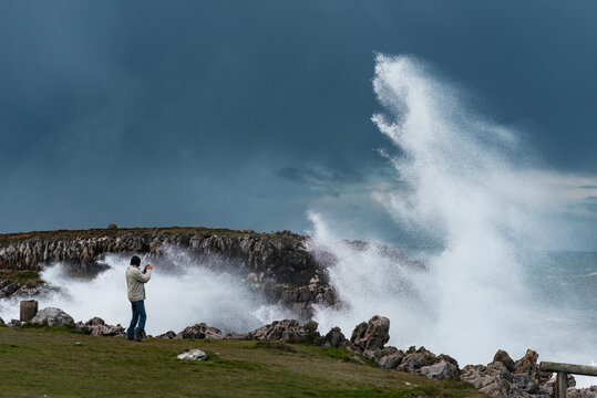 Traveler taking photo of stormy sea 