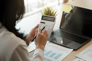 businesswoman working on desk office with using a calculator to calculate the numbers, finance...
