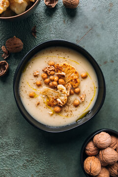 Cauliflower creamy soup topped with roasted cauliflower, chickpeas and walnuts