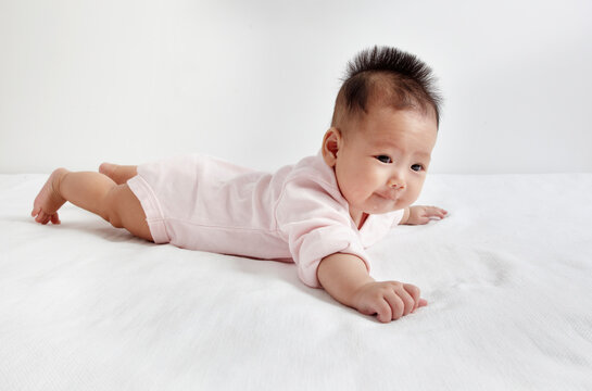 Close-up of a cute Asian baby playing on the bed