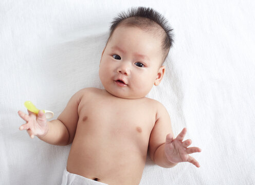 Cute Asian baby playing on the bed by herself, overhead shot