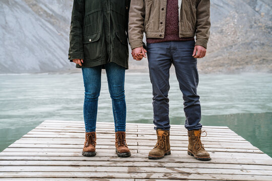 Anonymous Couple on wooden dock in frozen lake in mountain