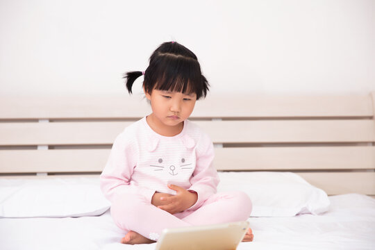 Cute Chinese Little Girl Watching Ipad In Bed