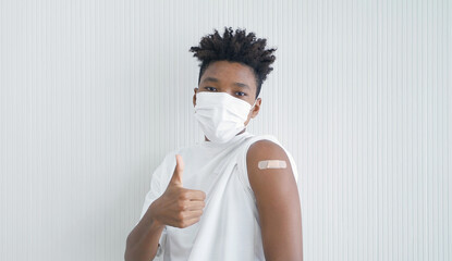 Portrait of happy young black African American teenager wearing a face mask, showing an arm with...