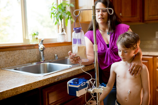 Mother checks formula bag as son is tube-fed with a pump