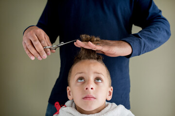 Father trims son's hair at home