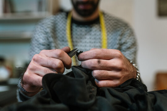 Close-up of a man cutting thread on a pice of clothing