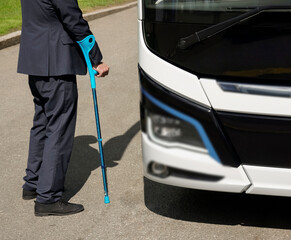 man with limited mobility taking a bus at a bus stop. no face.  handicapped or physically challenged young male  wait for bus in a station