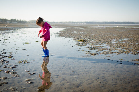 Girl in boots wading in shallow water 
